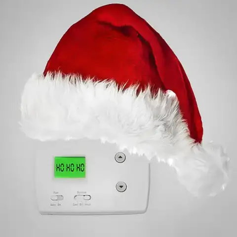 A thermostat covered with a santa hat.