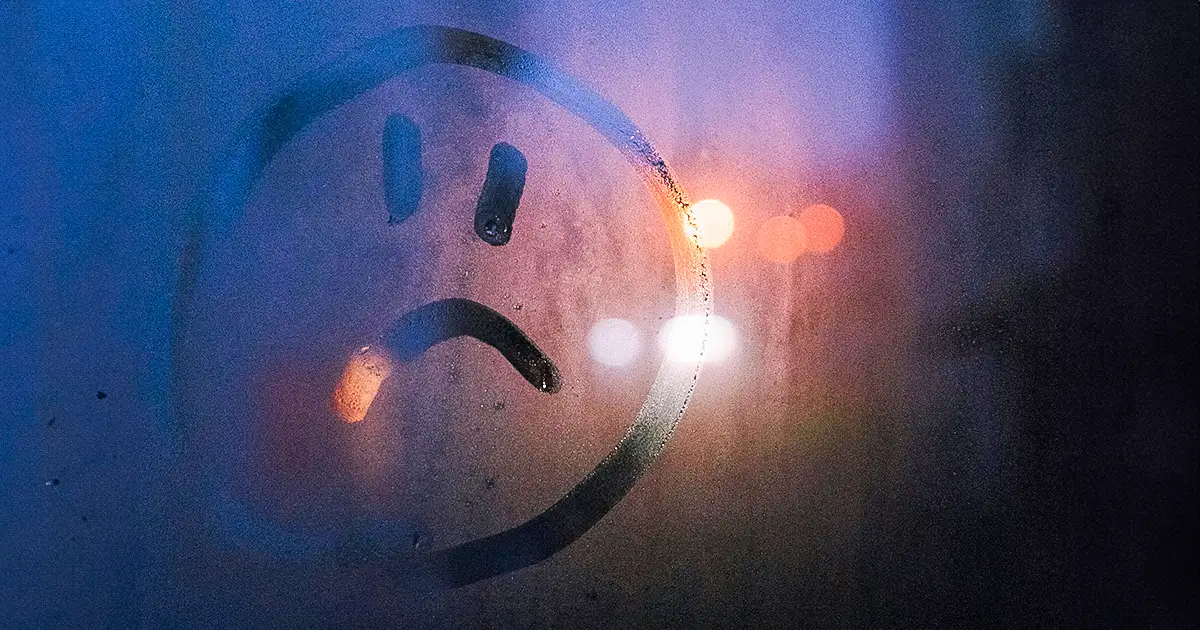 Condensation on a window, and an unhappy face drawn onto it.